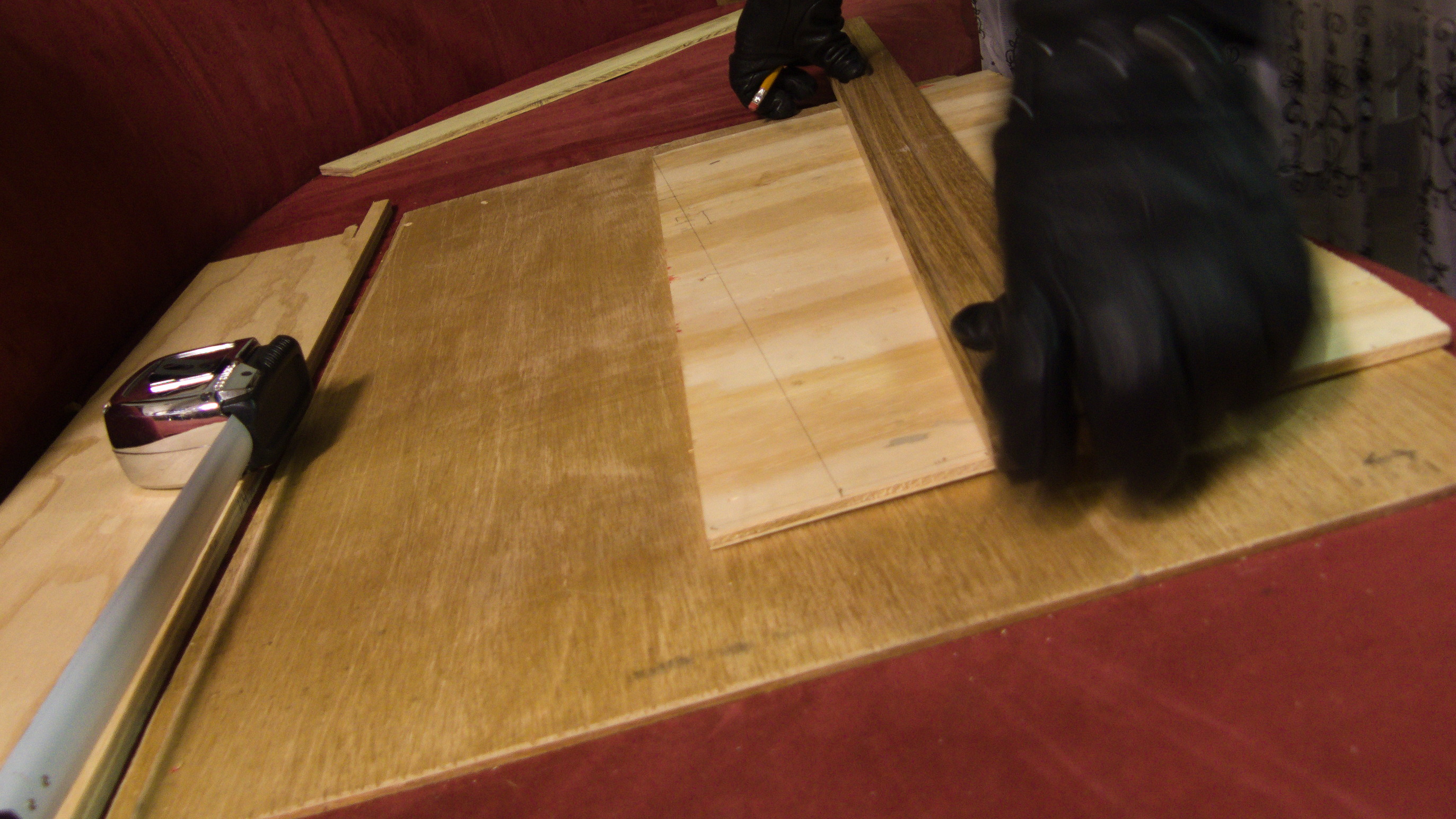 a pair of leather gloves measuring a plank of wood.