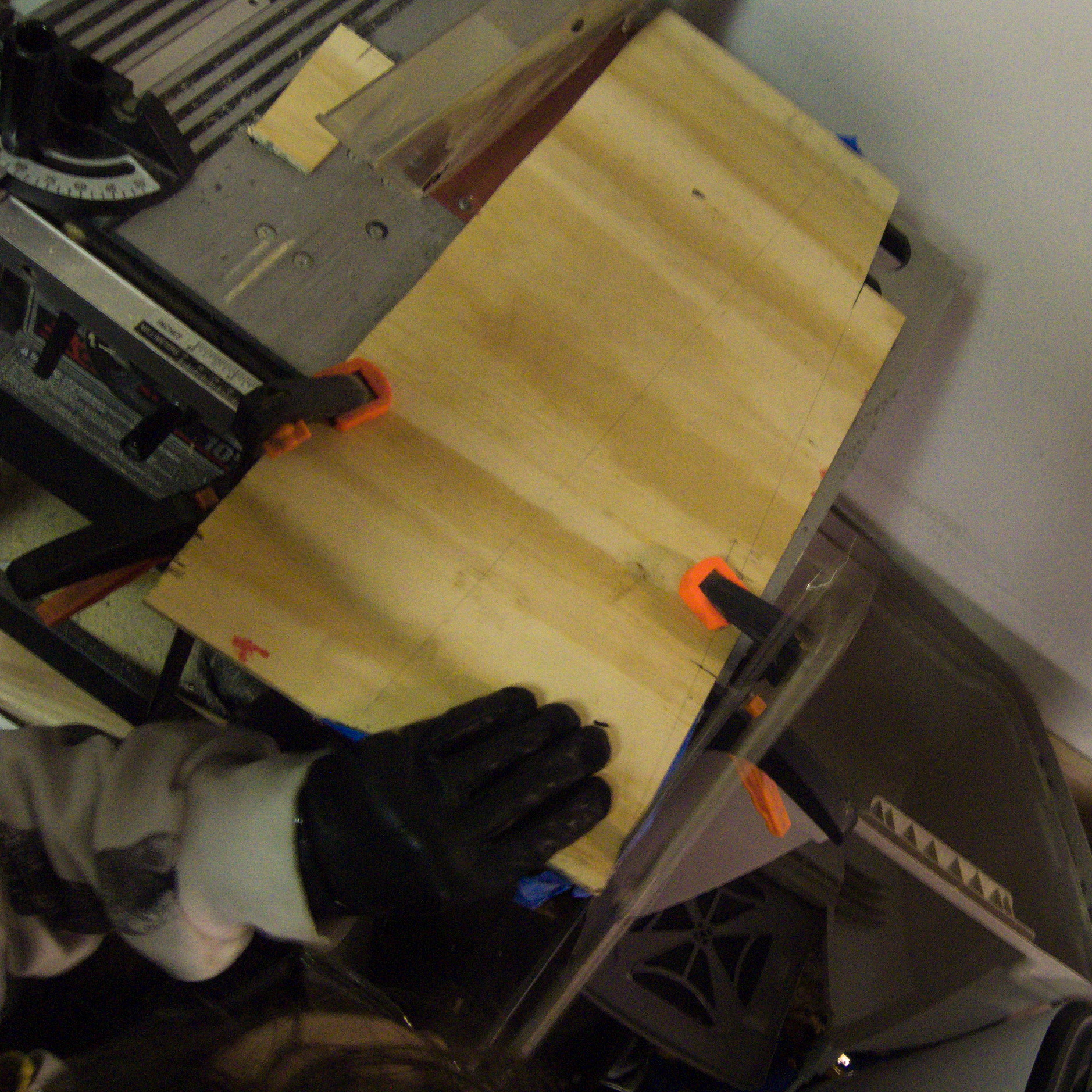 plank of wood clamped to table saw but being cut with a hand saw.